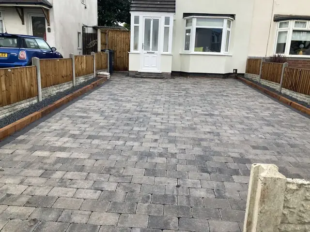 Grey block paved front driveway with timber fencing either side