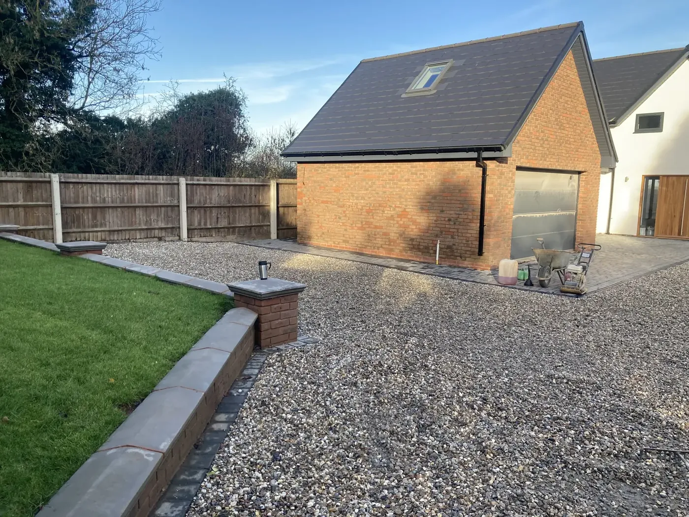 Gravel driveway finished with a brick pier, low wall and kerb edging